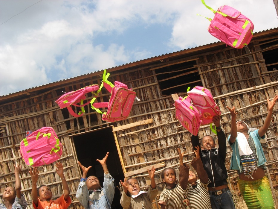 A group of children throwing pink school bags

Description automatically generated