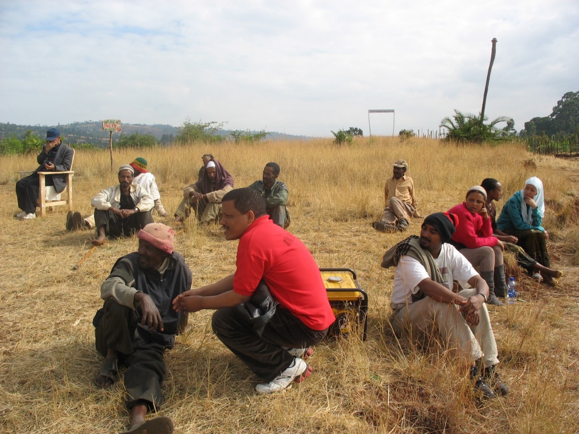 A group of people sitting in a field

Description automatically generated