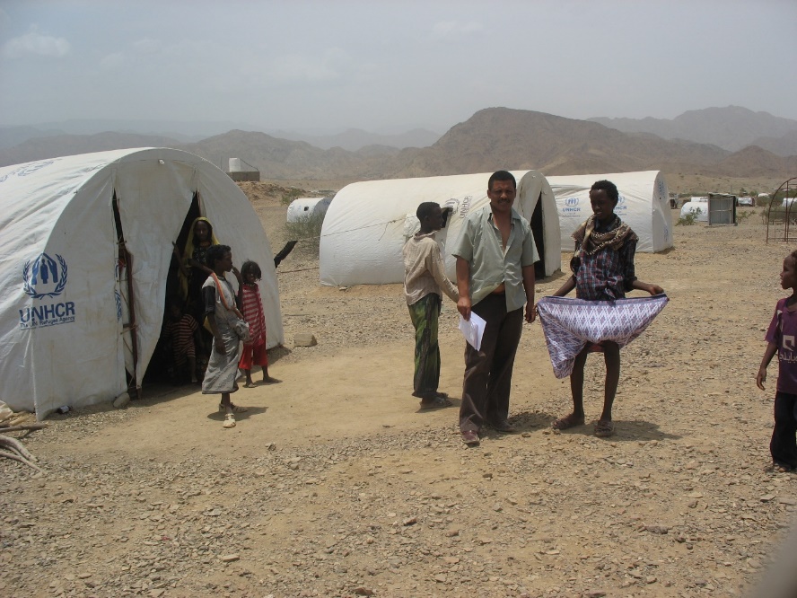 A group of people standing outside of tents

Description automatically generated